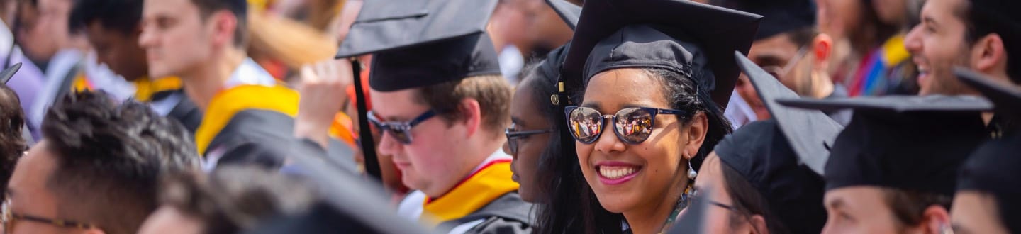 Woman with sunglasses and graduation cap smiling